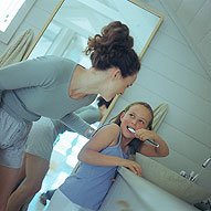 Pediatric dentist examining young child's teeth in clinical dental office setting.