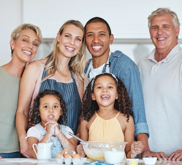 Happy multi-generational family smiling together in a bright, clean kitchen setting.
